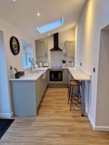 a large kitchen with white cabinets and a sink at Riverbank Cottage, Dog Friendly. Swansea, Llanelli in Hendy