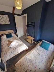 um quarto com 2 camas e uma parede azul em Riverbank Cottage, Dog Friendly. Swansea, Llanelli em Hendy