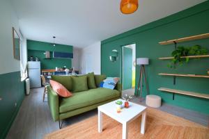 uma sala de estar com um sofá verde e uma mesa em Le Relais Poitevin - Grand T3 proche gare em Poitiers