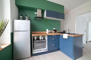 La cuisine est équipée de placards bleus et d'un réfrigérateur blanc. dans l'établissement Le Relais Poitevin - Grand T3 proche gare, à Poitiers