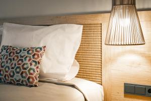 a pillow sitting on a bed with a lamp at htop Amatista #htopBliss in Lloret de Mar