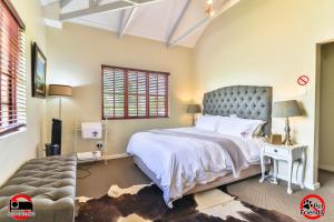a bedroom with a large bed and a chair at Cinzaco Dullstroom in Dullstroom