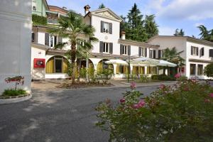 a large white building with a palm tree and flowers at Hotel Ristorante La Grotta in Castiglione delle Stiviere