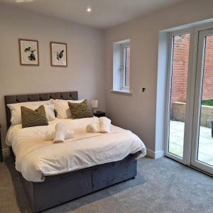 a bedroom with a large bed with white sheets at Home at Highgrove - Private Garden & Parking in Reading