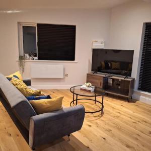 a living room with a couch and a tv at Home at Highgrove - Private Garden & Parking in Reading