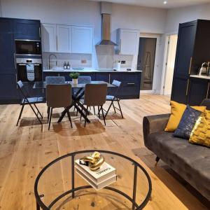 a living room with a couch and a table and a kitchen at Home at Highgrove - Private Garden & Parking in Reading
