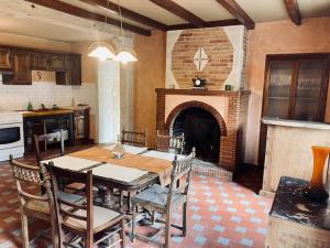 a kitchen with a dining table and a fireplace at Maison de campagne - La Belle Claudine in Laruscade