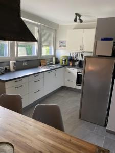 eine Küche mit weißen Schränken, einem Tisch und einem Kühlschrank in der Unterkunft WorkersHome in Ascheberg