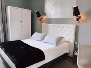 a bedroom with a white bed with a black blanket at Royal Hôtel in Nîmes