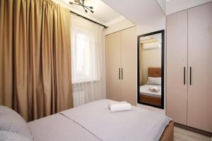 ein Schlafzimmer mit einem Bett und einem großen Spiegel in der Unterkunft Апартаменты в центре Алматы in Almaty