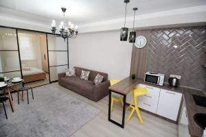 eine Küche und ein Wohnzimmer mit einem Sofa und einem Tisch in der Unterkunft Апартаменты в центре Алматы in Almaty