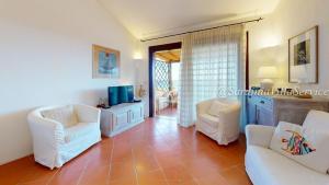 a living room with two white chairs and a tv at Appartamento Dream - Cala Granu in Porto Cervo