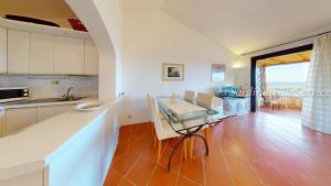 a kitchen with a counter and a table with chairs at Appartamento Dream - Cala Granu in Porto Cervo