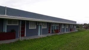 un edificio azul con puertas rojas y un campo verde en Toafa Lodge en ‘Ohonua