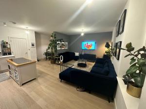 a living room with a blue couch and a tv at West London Hideaway Suite in Ealing