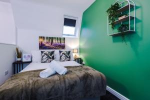 a bedroom with a large bed with a green wall at Charming abode near city centre/free parking in Liverpool