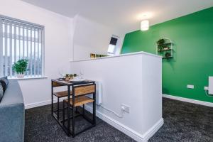 a living room with a green wall and a table at Charming abode near city centre/free parking in Liverpool
