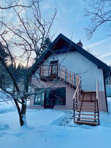 a house with a wooden staircase in the snow at Apartament W Dolinie Modrzewi in Kamienna Góra