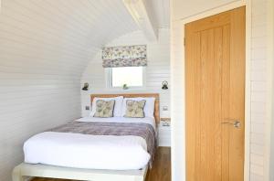 a small bedroom with a bed and a door at Luxury Glamping Pods - The Heft & The Hirsel in Glasgow