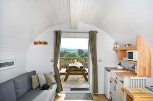 a living room with a couch and a kitchen with a table at Luxury Glamping Pods - The Heft & The Hirsel in Glasgow