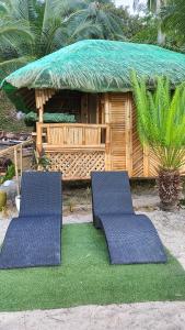 two chairs sitting on grass in front of a building at NATUA'S BEACH RESORT in Liminangcong