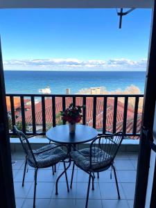 stół i krzesła na balkonie z widokiem na ocean w obiekcie Aegean View House w mieście Agios Ioannis Pelio
