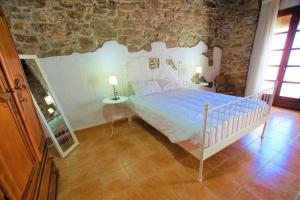 1 dormitorio con cama y pared de piedra en V&V Lloret-CAL MIQUEL exclusiva casa de pueblo a 10 metros de la playa de Blanes y La Palomera!!, en Blanes