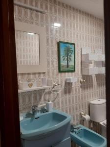 uma casa de banho com um lavatório azul e um WC. em La Casa Céntrica Gijón em Gijón
