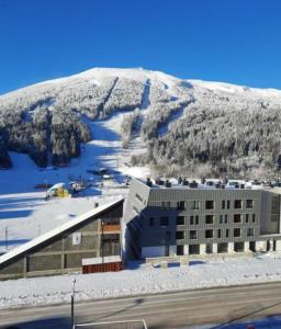 a building in front of a snow covered mountain at Sara Sarajevo in Bjelašnica