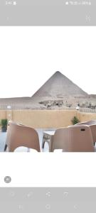 Tamara Pyramids Inn في القاهرة: اطلالة على الاهرامات من طاولة مع كراسي