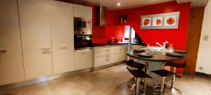 a kitchen with red walls and a table and chairs at Le Petit Prieuré Langeais in Langeais