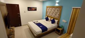 a small bedroom with a bed with blue walls at Hotel Dhruv Palace Bangalore Jakkur in Bengaluru