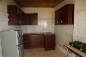 a kitchen with wooden cabinets and a refrigerator at Kigali guesthouse: shared property with individual rooms in Kigali