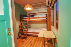 Kleines Zimmer mit Etagenbetten und einem Tisch in der Unterkunft HOSTEL CHILLAX in Osaka