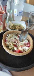 a pizza sitting on a table with a spoon at Tinian View Bee Home Maisonette in Arnados
