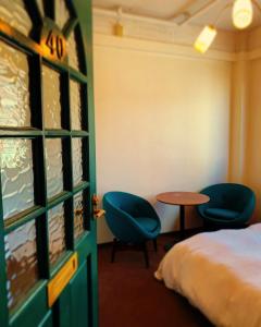 a room with a bed and two chairs and a table at Riverside HOSTEL CHILLAX Namba in Osaka