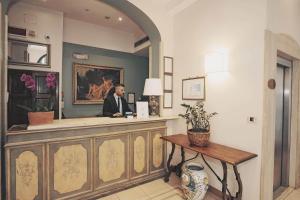 Un homme en costume assis au comptoir dans l'établissement Hotel Galileo, à Florence