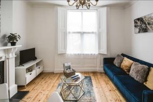 a living room with a blue couch and a window at Spacious 4 bed house in Croydon w/ parking for x2 cars! - Photo ID required in South Norwood