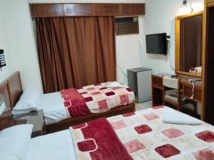 a hotel room with two beds and a desk at Merryland Hotel Luxor in Luxor
