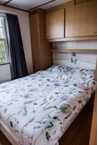 uma cama com um edredão floral num quarto em Chalet Zeeuws Genieten in Baarland, Zeeland em Baarland