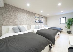 a bedroom with four beds and a wall at Rei Garden Resort in Kanayama
