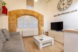 uma sala de estar com um sofá e um relógio na parede em Studio Cardeurs em Aix-en-Provence