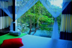 a bedroom with a window with a view of a river at Sunwin River Cabana in Udawalawe