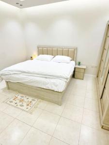 a bedroom with a bed with white sheets and pillows at شقة جميلة بغرفتين نوم ودخول ذاتي ١١ in Riyadh