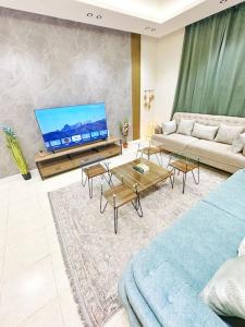 a living room with a couch and a flat screen tv at شقة جميلة بغرفتين نوم ودخول ذاتي ١١ in Riyadh