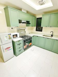 a kitchen with green cabinets and a stove and refrigerator at شقة جميلة بغرفتين نوم ودخول ذاتي ١١ in Riyadh