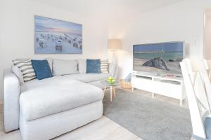 a living room with a white couch and a tv at Fischerhus in Timmendorfer Strand