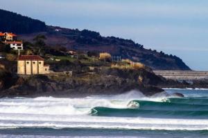 a group of waves in the ocean with a house at Soul Etxia in Bermeo +6 photos