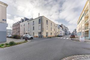 una strada vuota con edifici e un'auto sulla strada di La Secrète - Bel appartement mansardé a Nantes