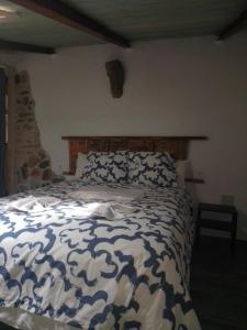 Schlafzimmer mit einem Bett mit einer blauen und weißen Bettdecke in der Unterkunft CASA CARMELA in Higuera de la Sierra